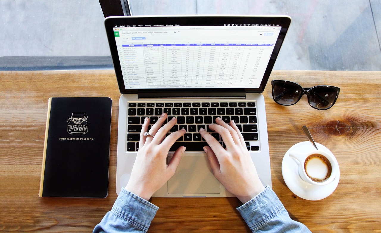 Hands typing on a laptop, with a notebook and coffee, symbolizing building a desktop application.